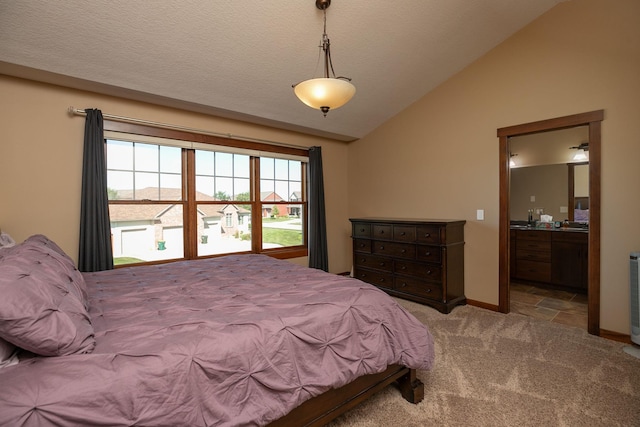 bedroom with light carpet, a textured ceiling, lofted ceiling, and ensuite bath