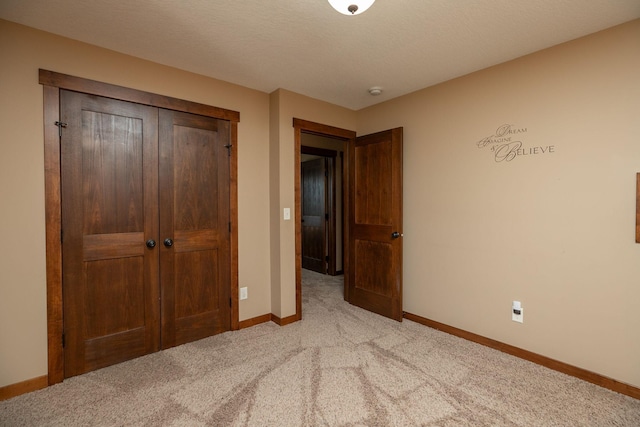 unfurnished bedroom with a closet, light colored carpet, and a textured ceiling