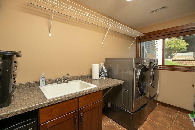 clothes washing area featuring dark tile patterned floors, sink, a textured ceiling, cabinets, and independent washer and dryer