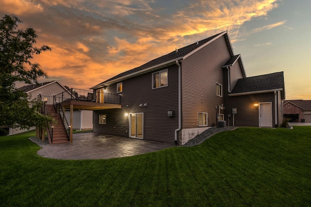 back house at dusk with a patio, cooling unit, a yard, and a deck