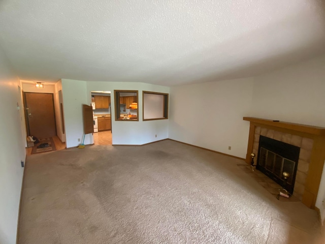 unfurnished living room with a textured ceiling, light carpet, and a fireplace