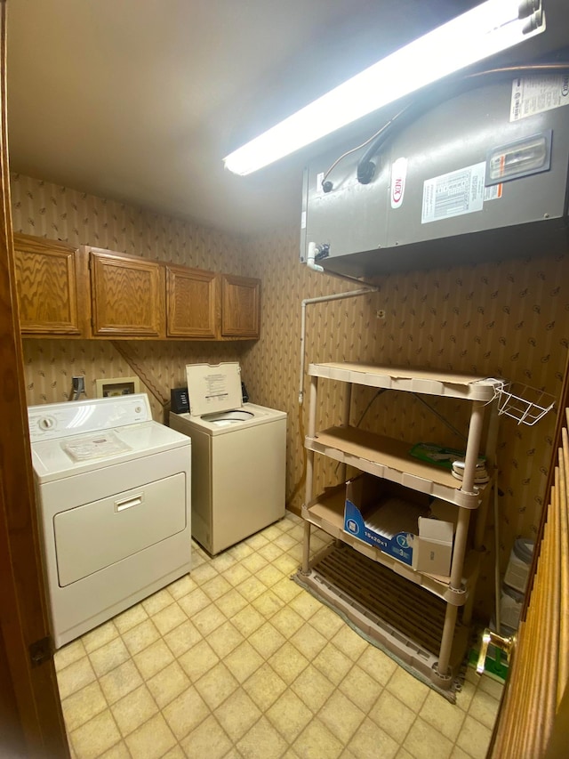 clothes washing area featuring cabinets, washer and clothes dryer, and light tile patterned floors