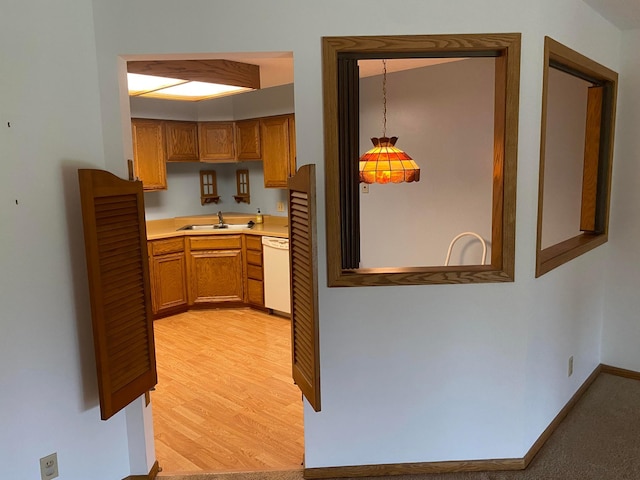 kitchen with sink, dishwasher, pendant lighting, and light wood-type flooring