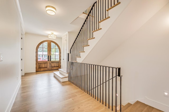 foyer entrance featuring light hardwood / wood-style floors, french doors, and crown molding