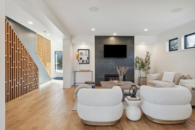 living room featuring a tile fireplace and light hardwood / wood-style floors