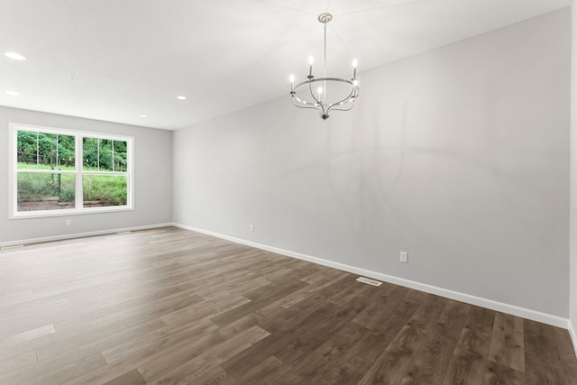 spare room featuring hardwood / wood-style flooring and a notable chandelier