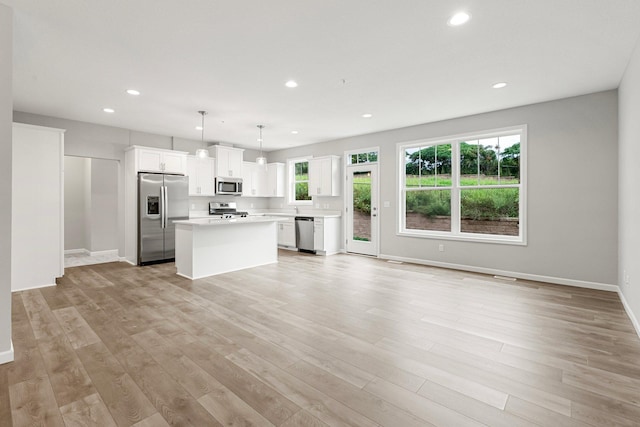 kitchen with a healthy amount of sunlight, light wood-type flooring, appliances with stainless steel finishes, and white cabinetry