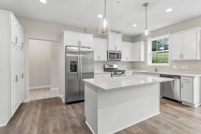 kitchen with light wood-type flooring, white cabinets, pendant lighting, and stainless steel appliances