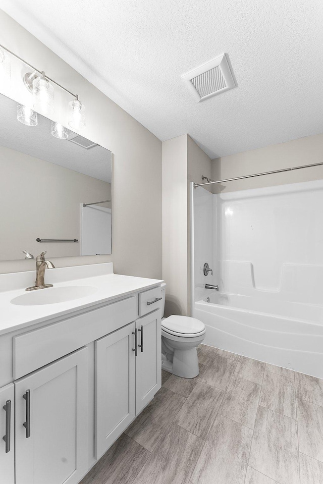 full bathroom with a textured ceiling, vanity, toilet, shower / bathtub combination, and tile patterned floors