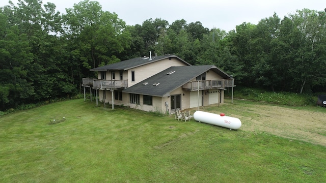 back of property featuring a lawn, a garage, and a deck