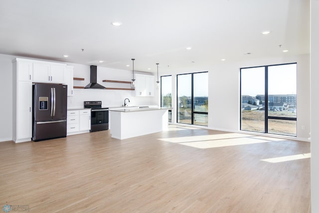 kitchen featuring white cabinets, stainless steel refrigerator with ice dispenser, wall chimney exhaust hood, decorative light fixtures, and black range with electric cooktop