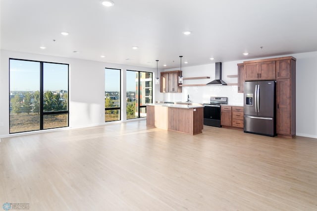 kitchen featuring appliances with stainless steel finishes, hanging light fixtures, a center island, and light hardwood / wood-style flooring