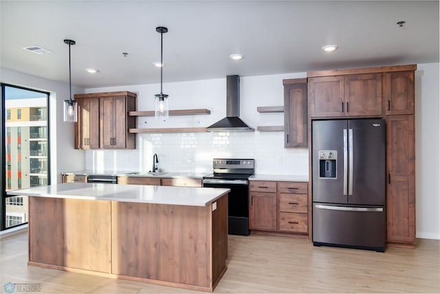 kitchen with hanging light fixtures, a kitchen island, wall chimney range hood, black range with electric cooktop, and stainless steel fridge