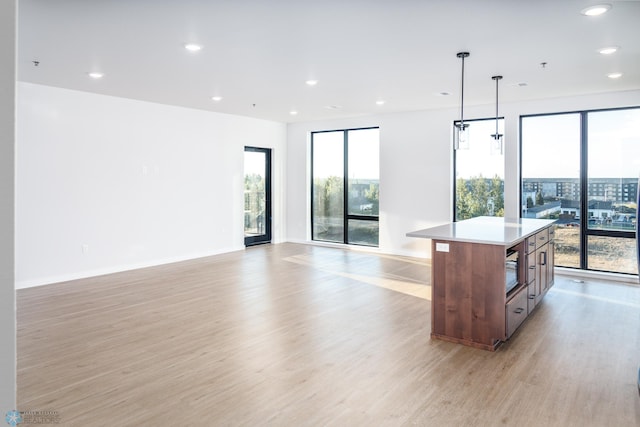 kitchen with light hardwood / wood-style floors, plenty of natural light, a kitchen island, and decorative light fixtures