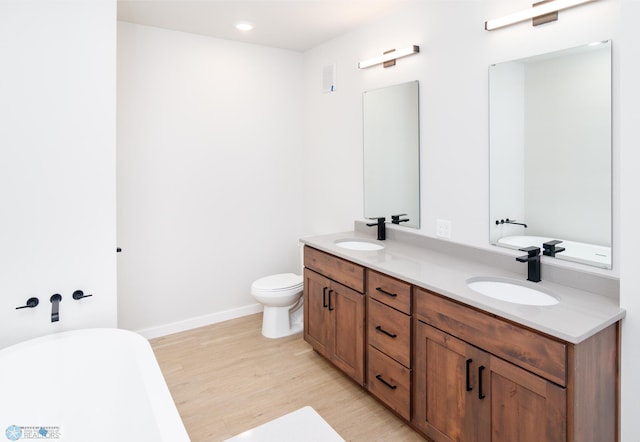 bathroom with wood-type flooring, vanity, toilet, and a tub