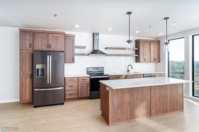 kitchen with wall chimney exhaust hood, pendant lighting, stainless steel appliances, light wood-type flooring, and sink