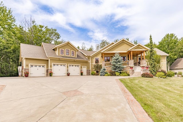 craftsman-style house featuring an attached garage, stone siding, a front yard, covered porch, and driveway