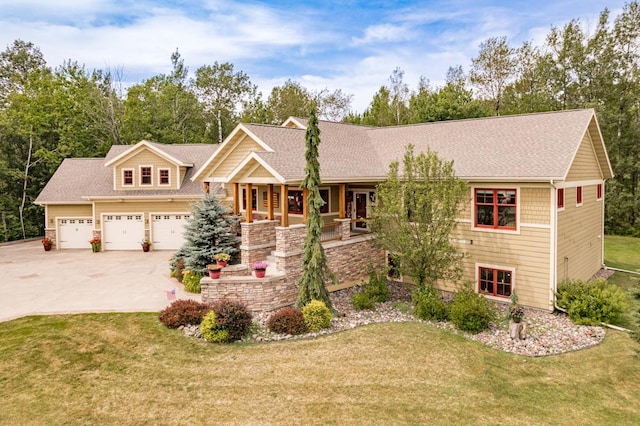 craftsman-style home featuring roof with shingles, covered porch, concrete driveway, and a front yard
