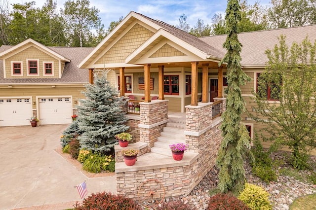 craftsman-style house with a shingled roof, an attached garage, stone siding, a porch, and driveway
