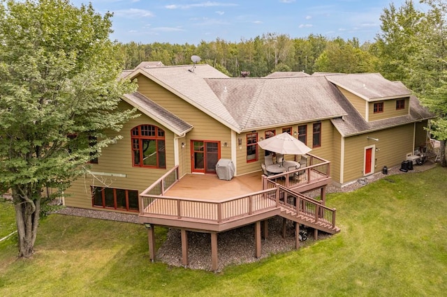 rear view of house featuring a shingled roof, a yard, and a deck