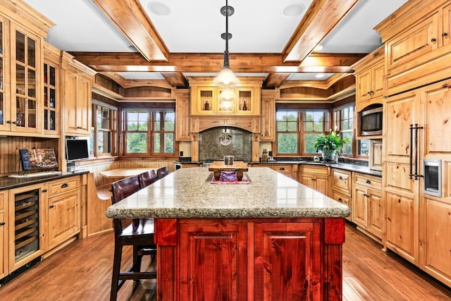 kitchen with a healthy amount of sunlight, a kitchen island, beverage cooler, and dark wood-type flooring