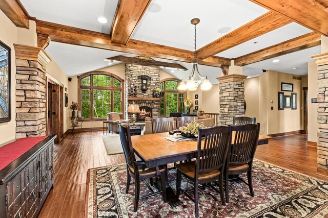 dining room with decorative columns, hardwood / wood-style floors, a fireplace, baseboards, and beamed ceiling