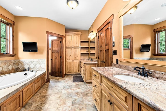 full bath with a garden tub, a sink, and two vanities
