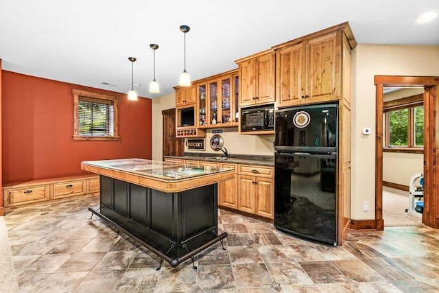kitchen with plenty of natural light, stone finish flooring, black appliances, and dark countertops