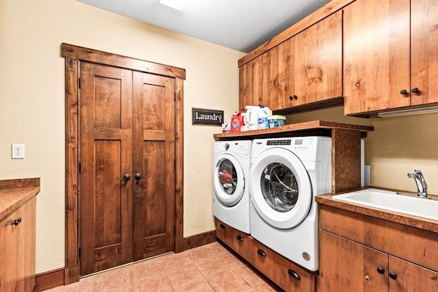 laundry room with independent washer and dryer, cabinet space, a sink, baseboards, and light tile patterned floors