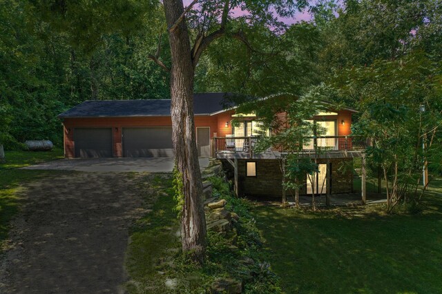 view of front of property with a wooden deck, a yard, and a garage