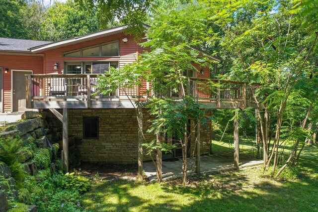 back of property featuring a wooden deck, a patio area, and a yard