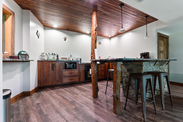 bar with black microwave, a bar, dark wood finished floors, and baseboards