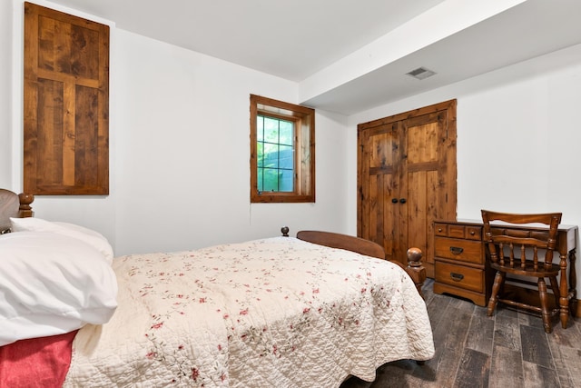 bedroom featuring dark wood-style floors, visible vents, and a closet