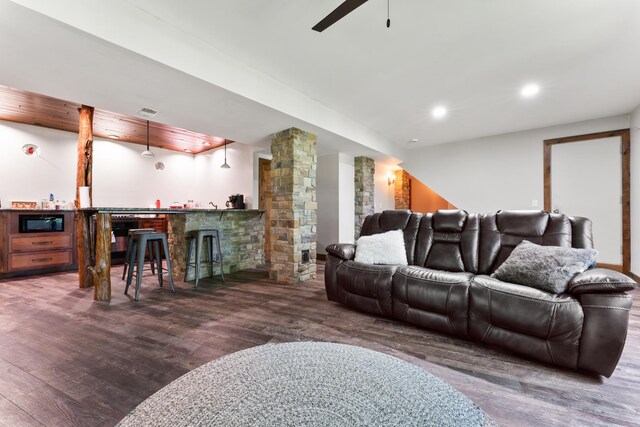 living room featuring decorative columns, bar area, and dark hardwood / wood-style floors