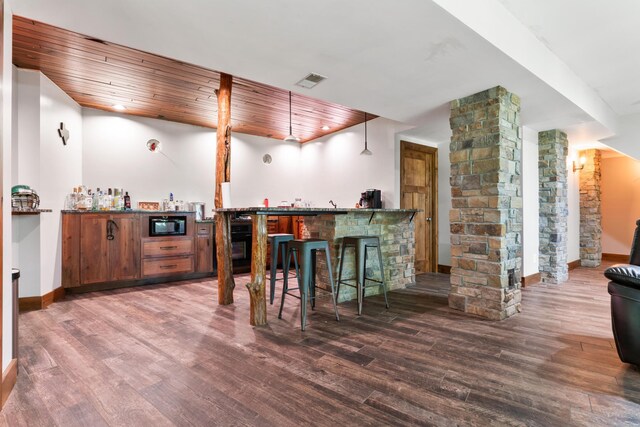 bar featuring wood ceiling, decorative light fixtures, dark wood-type flooring, and decorative columns