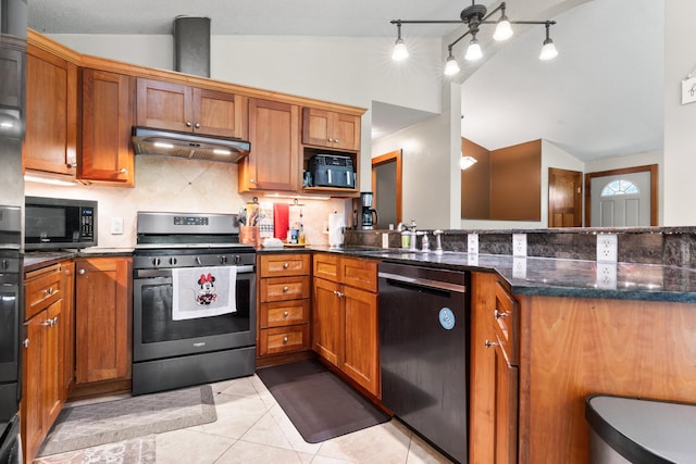 kitchen with lofted ceiling, decorative backsplash, light tile patterned floors, dark stone countertops, and stainless steel appliances