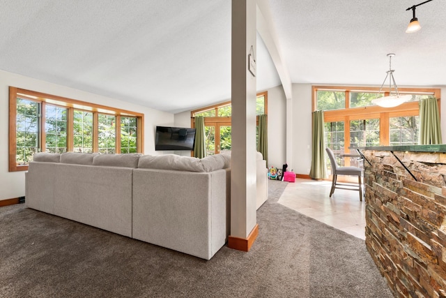 carpeted living room with baseboards, plenty of natural light, lofted ceiling with beams, and a textured ceiling