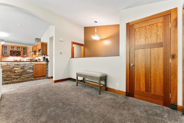 carpeted entryway featuring vaulted ceiling, baseboards, and indoor bar