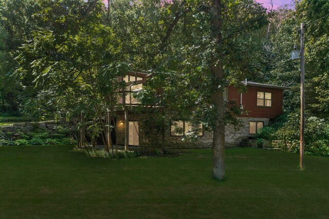 back house at dusk with a lawn