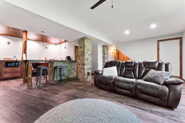 living room featuring dark wood-type flooring, indoor bar, and decorative columns