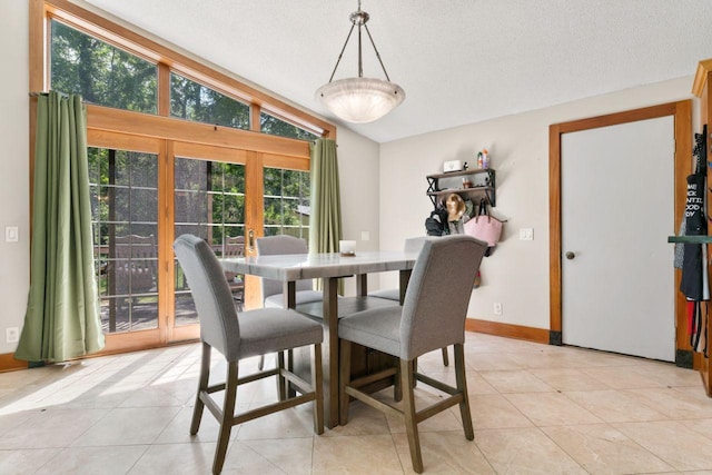 dining space with lofted ceiling, a textured ceiling, baseboards, and light tile patterned floors