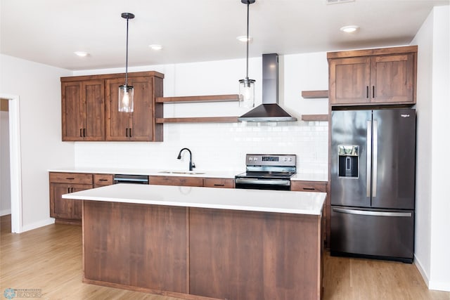 kitchen featuring appliances with stainless steel finishes, pendant lighting, light hardwood / wood-style flooring, sink, and wall chimney range hood