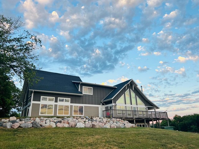 rear view of property featuring a lawn and a deck