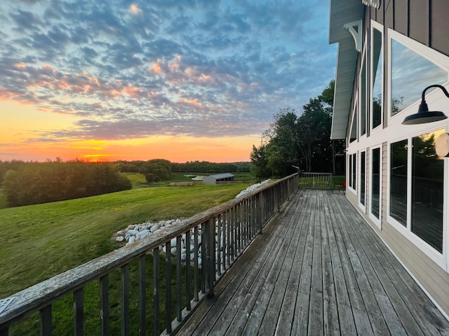 deck at dusk featuring a lawn