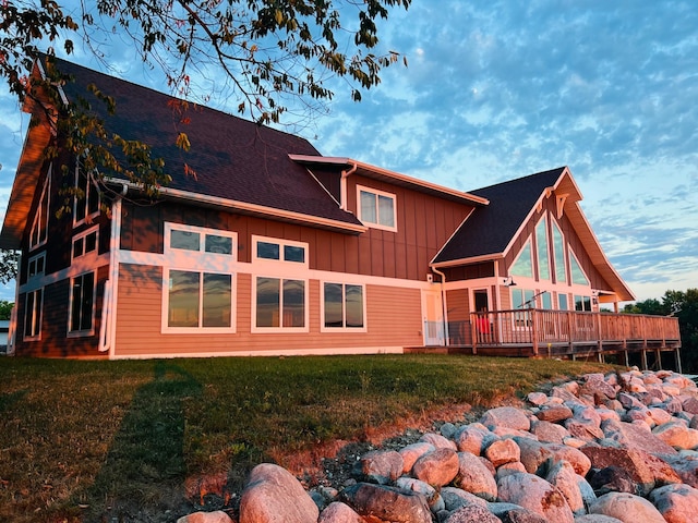 rear view of property featuring a wooden deck and a yard