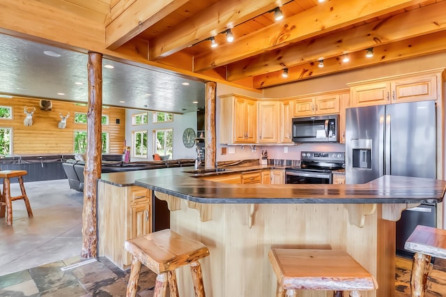 kitchen with light brown cabinets, stainless steel appliances, a breakfast bar, and beamed ceiling