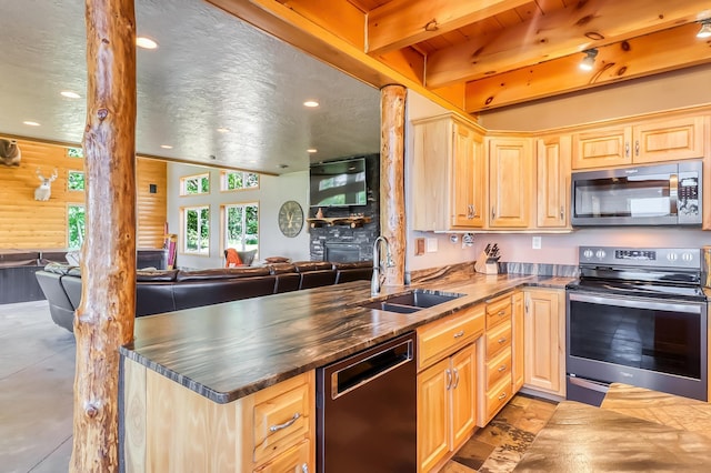 kitchen featuring a textured ceiling, kitchen peninsula, beamed ceiling, stainless steel appliances, and sink