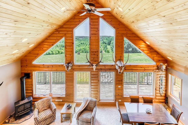 interior space featuring log walls, wooden ceiling, plenty of natural light, and a wood stove