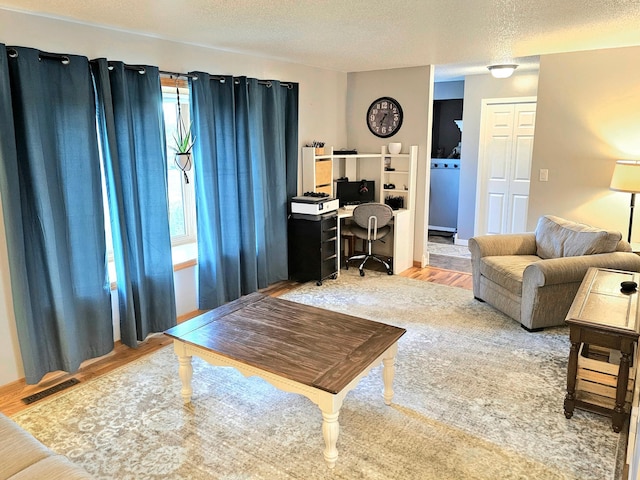 living room with a textured ceiling, light wood-type flooring, and a healthy amount of sunlight