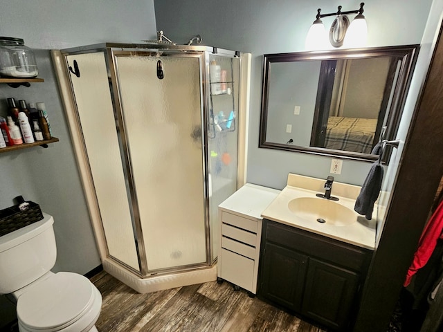 bathroom with vanity, toilet, a shower with door, and hardwood / wood-style flooring